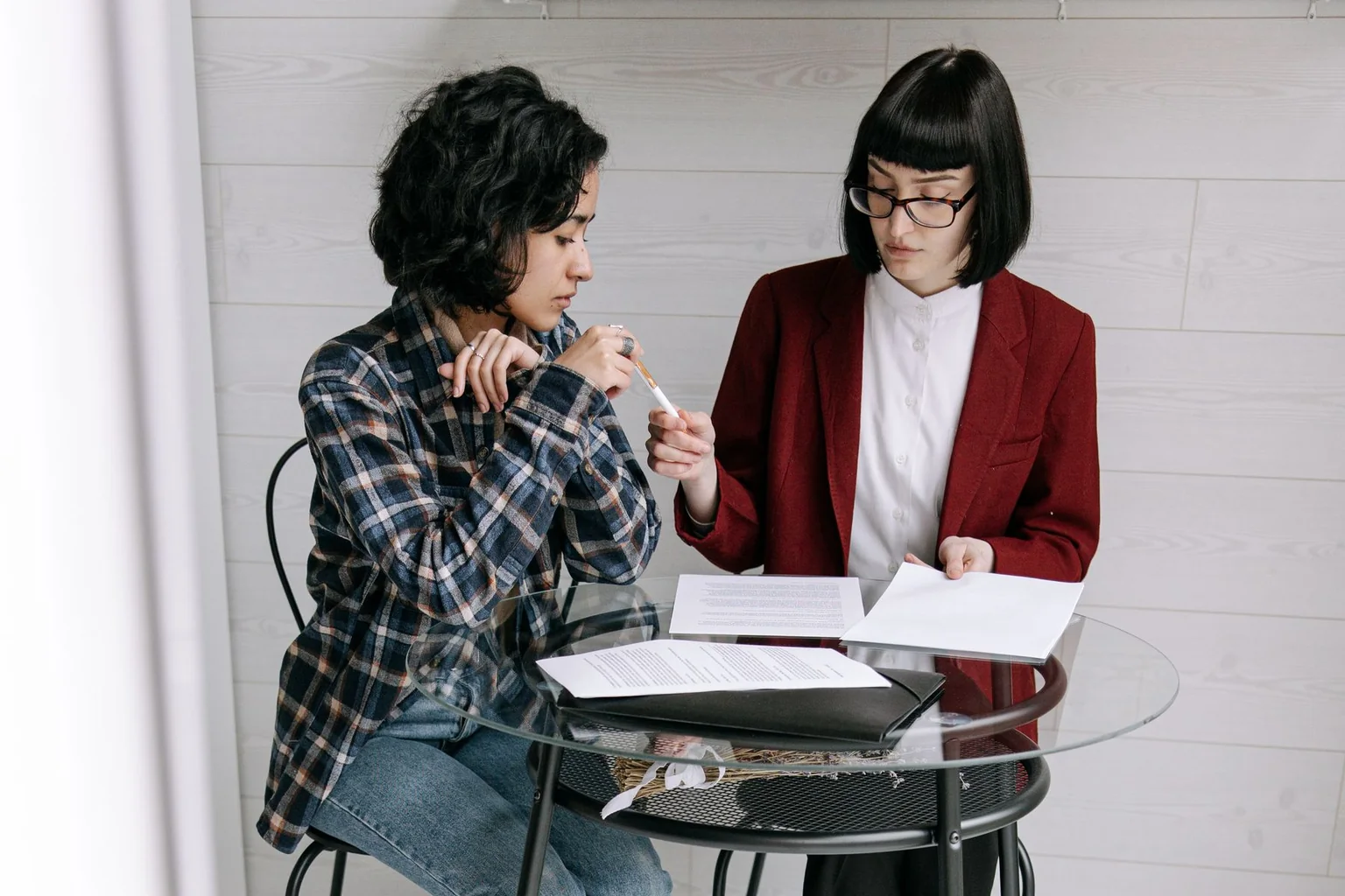 Dos profesionales revisando juntas varios documentos impresos